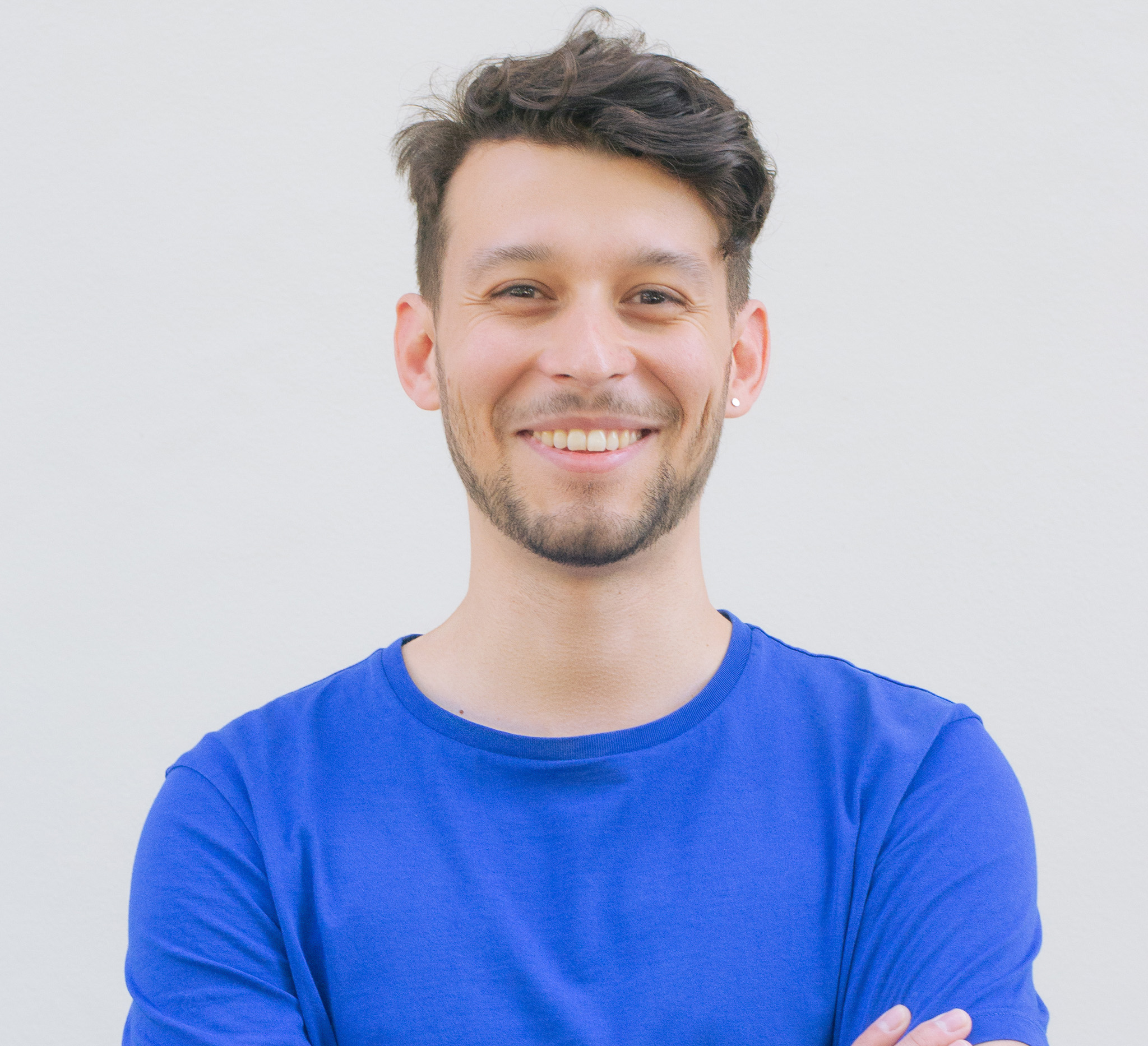 Portrait photo of Jose Rodriguez wearing a blue shirt standing in front of a white wall