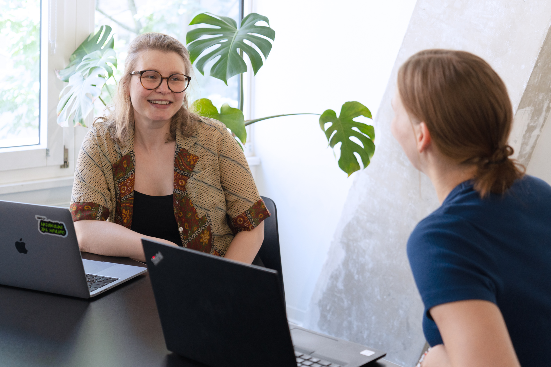 Julia, People Operations Managerin, und Lene, Senior Transformation Managerin, sitzen gmeinsam an einem Tisch im Büro des DigitalService und unterhalten sich