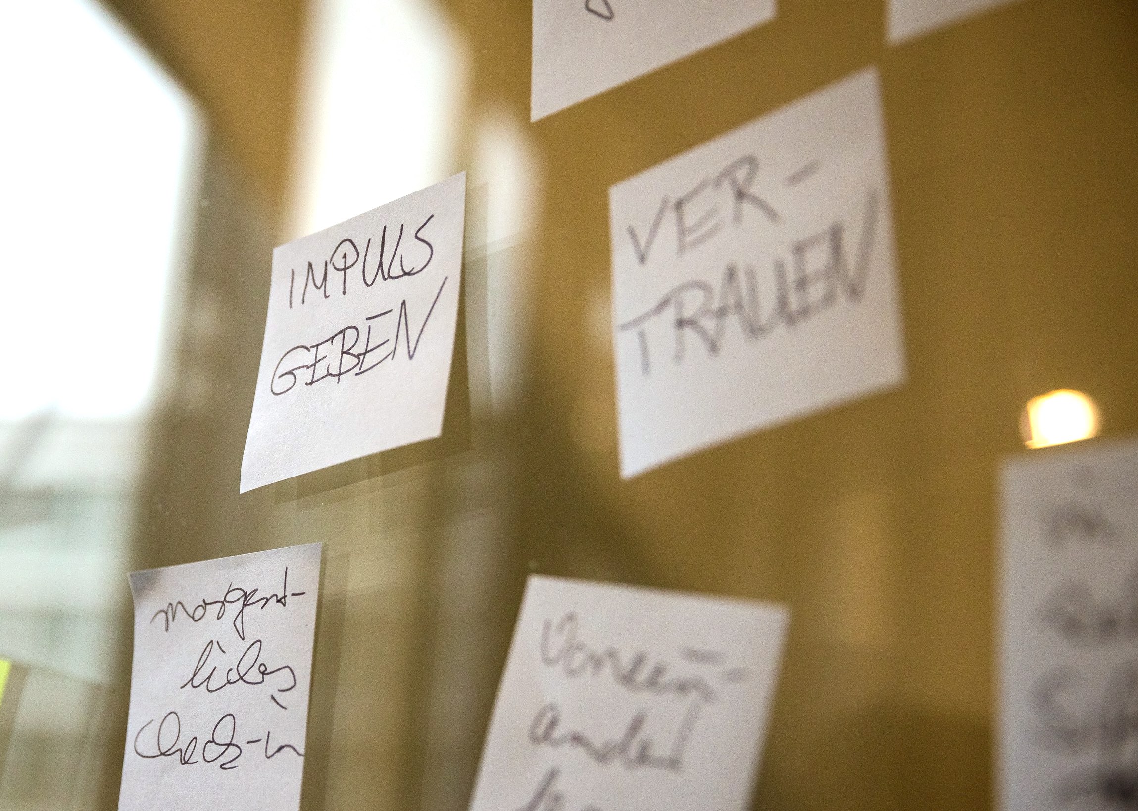 Nahaufnahme von verschiedenen Klebenotizen. Im Fokus ein Klebezettel mit der Aufschrift: Impuls geben.