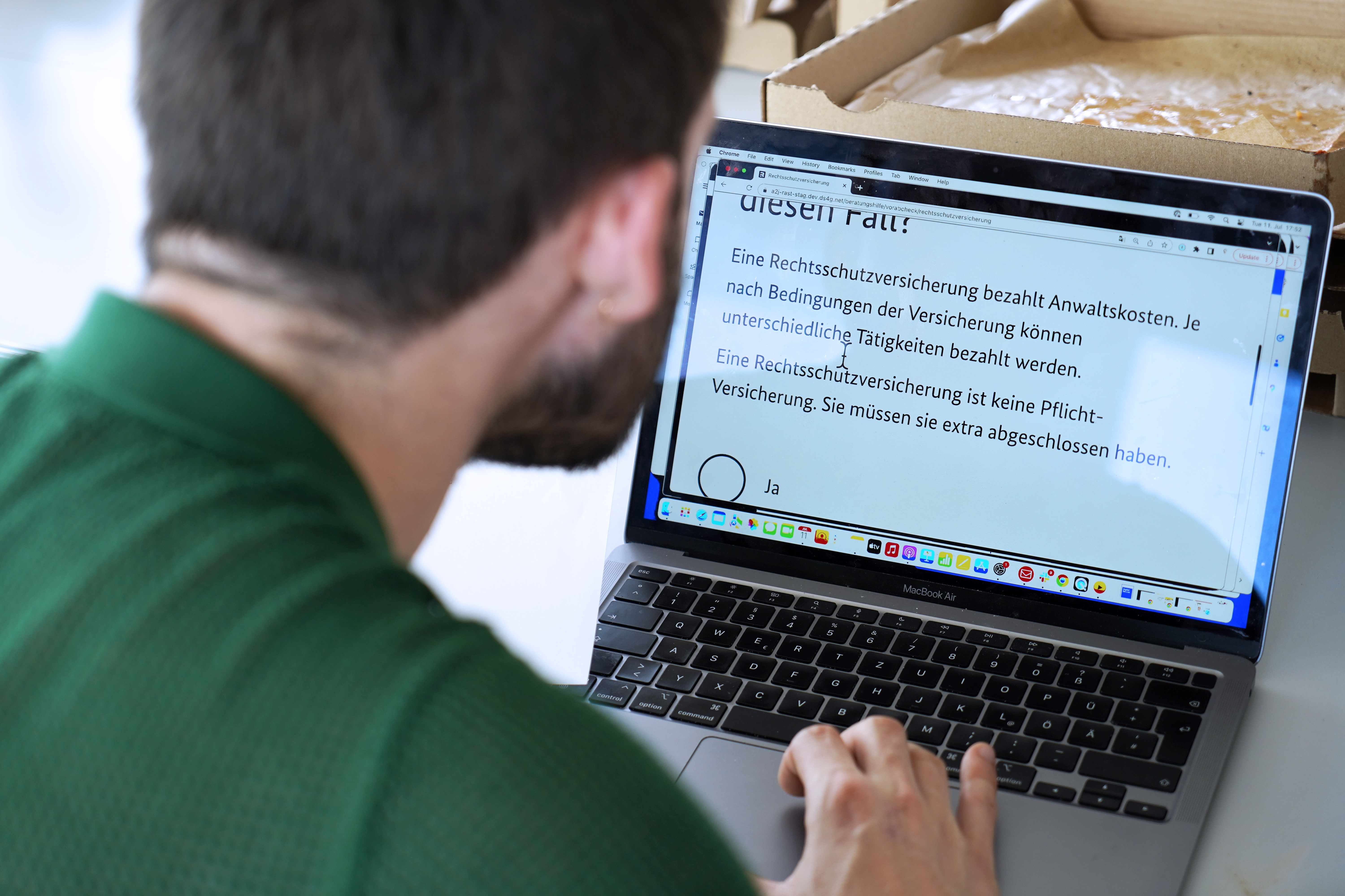 Eine Person vor einem Laptop-Computer, auf dem eine stark vergrößerte Beschreibung einer Rechtsschutzversicherung zu sehen ist