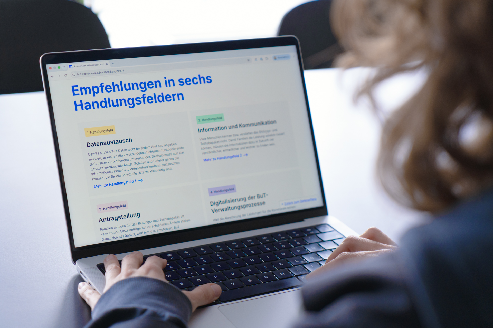 Eine Person vor einem Laptop, dessen Bildschirm die Projektwebsite anzeigt. Unter der Überschrift „Empfehlungen in sechs Handlungsfeldern“ werden die einzelnen Handlungsfelder benannt und vorgestellt.