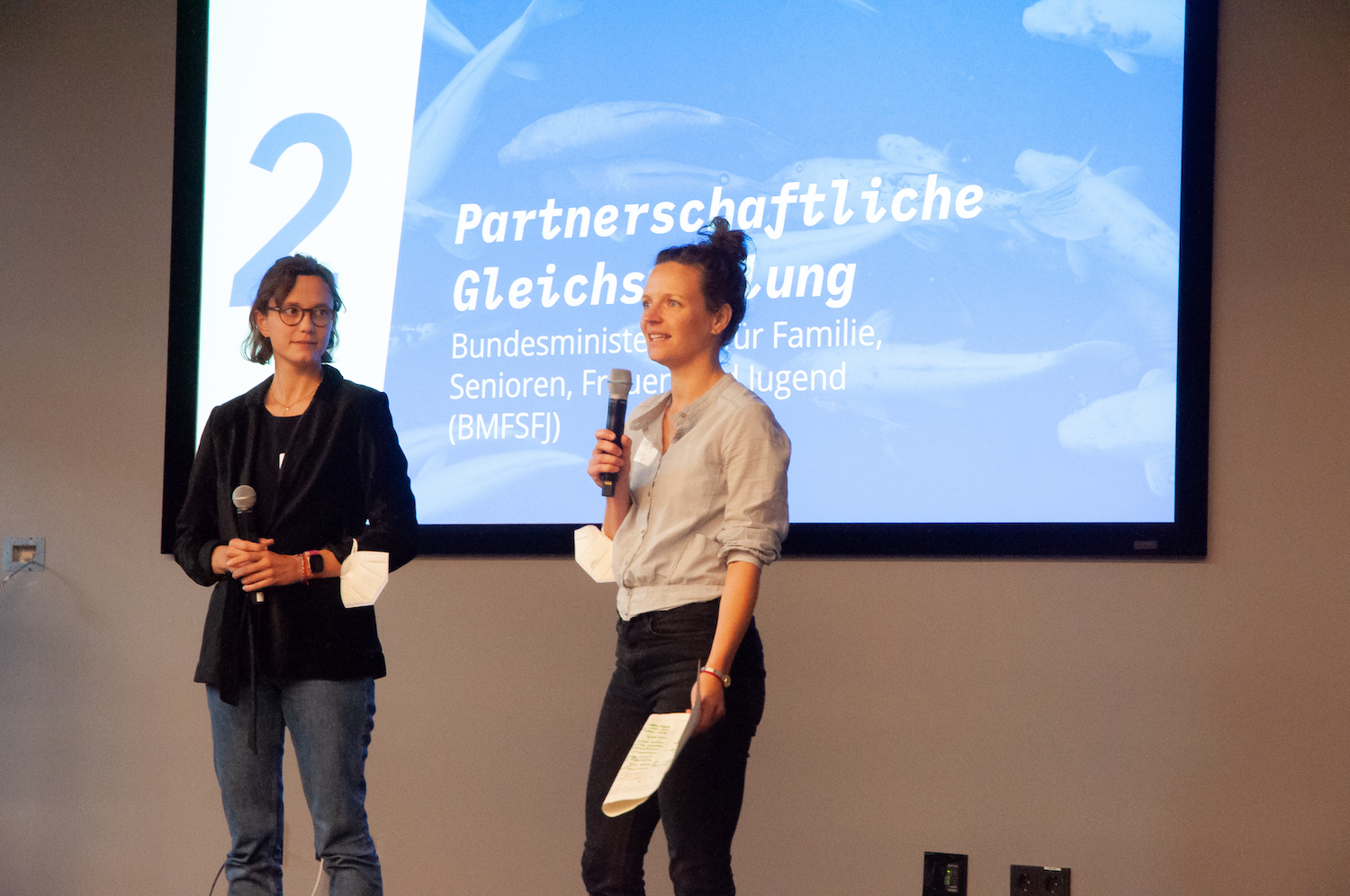 Zwei Frauen stellen auf einer Bühne ein Projekt vor