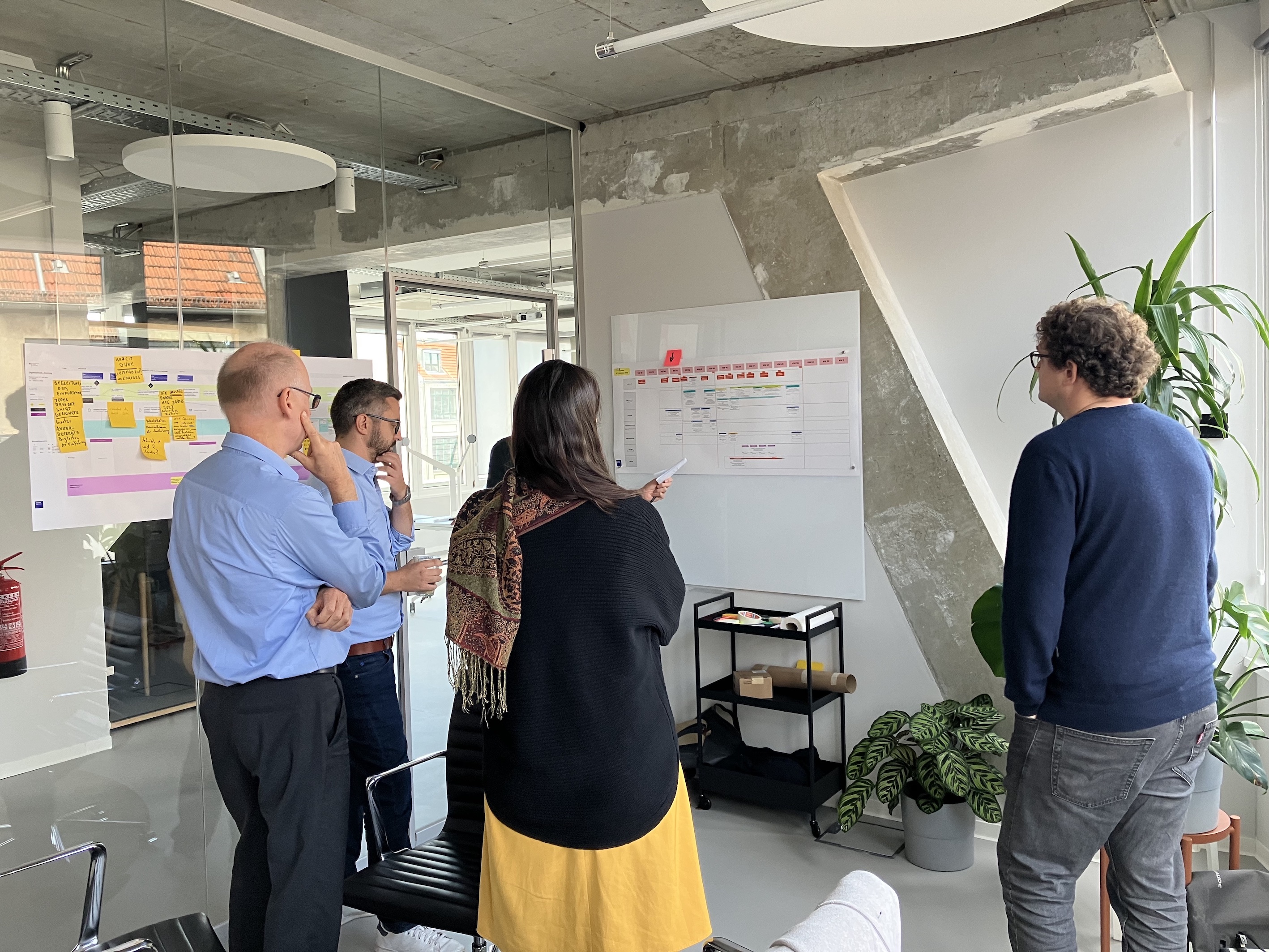 Vier Personen in einem Büroraum, die einen Projektplan besprechen