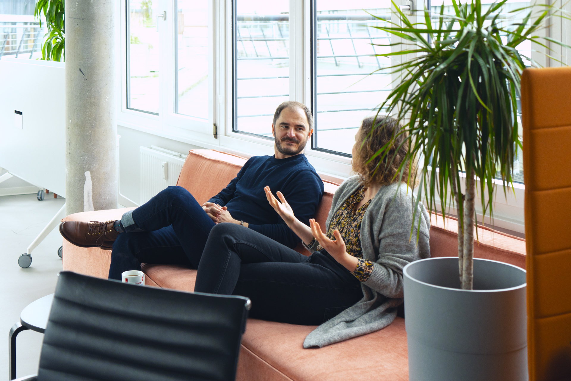 Zwei Personen sitzen auf einem Sofa und unterhalten sich.
