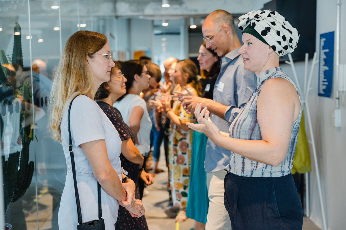 Mehrere Personen stehen in einem modernen Bürogang mit Glaswänden und reden miteinander.