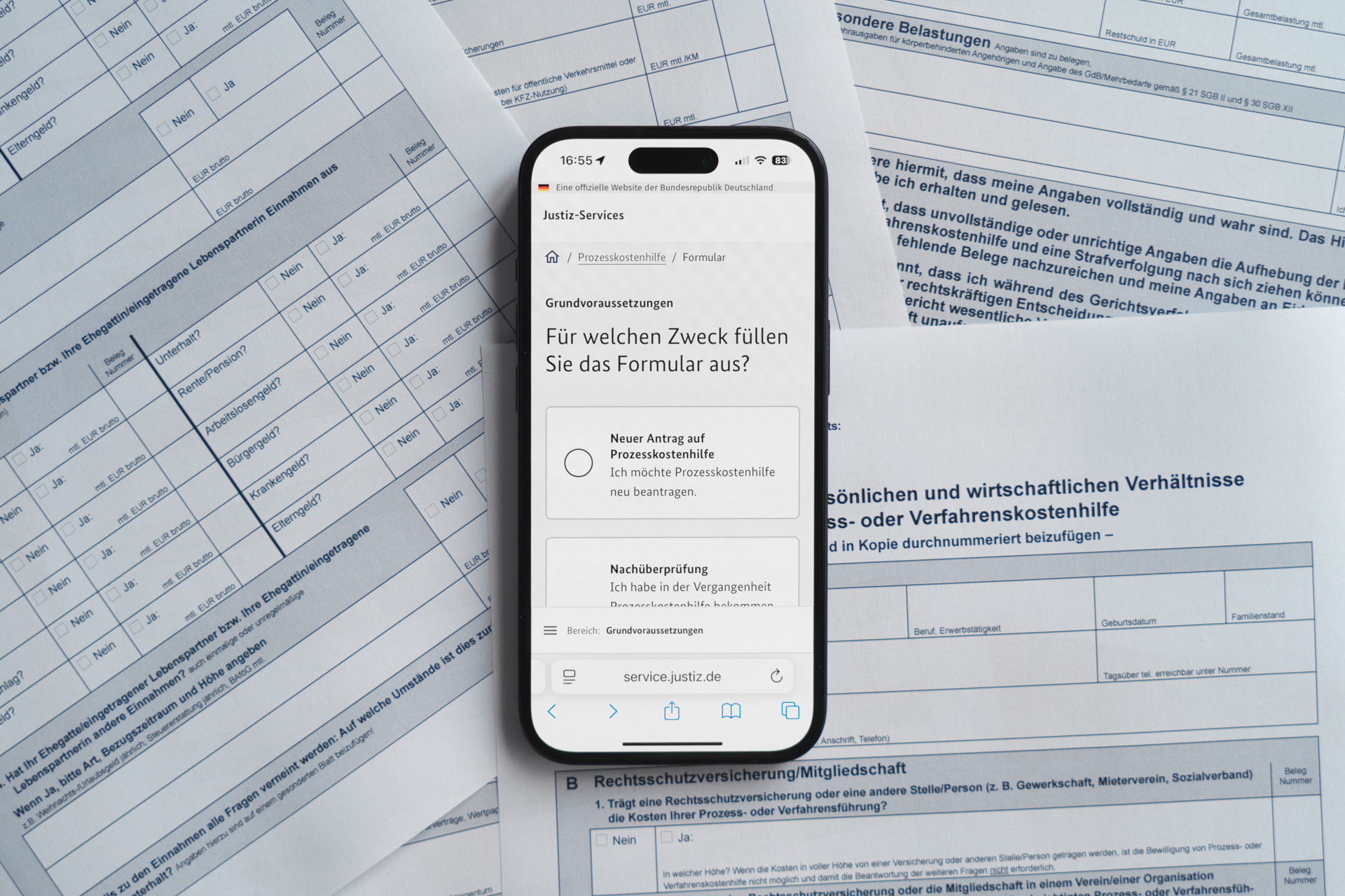 Ein Mobiltelefon liegt auf einem Stapel Formulare, auf dem Bildschirm steht: „Für welchen Zweck füllen sie das Formular aus?“