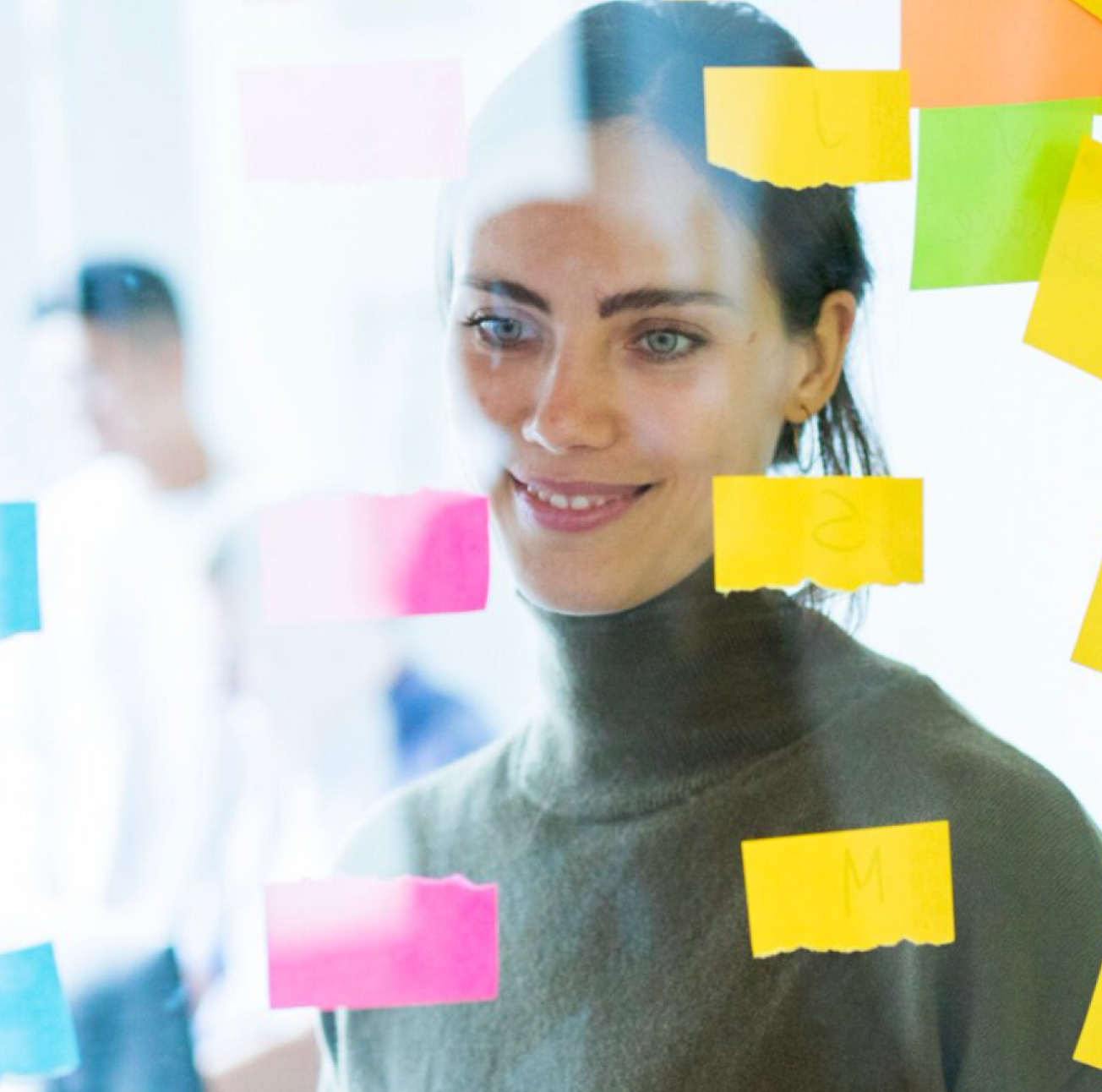 Frau steht hinter einer Scheibe mit Post-Its