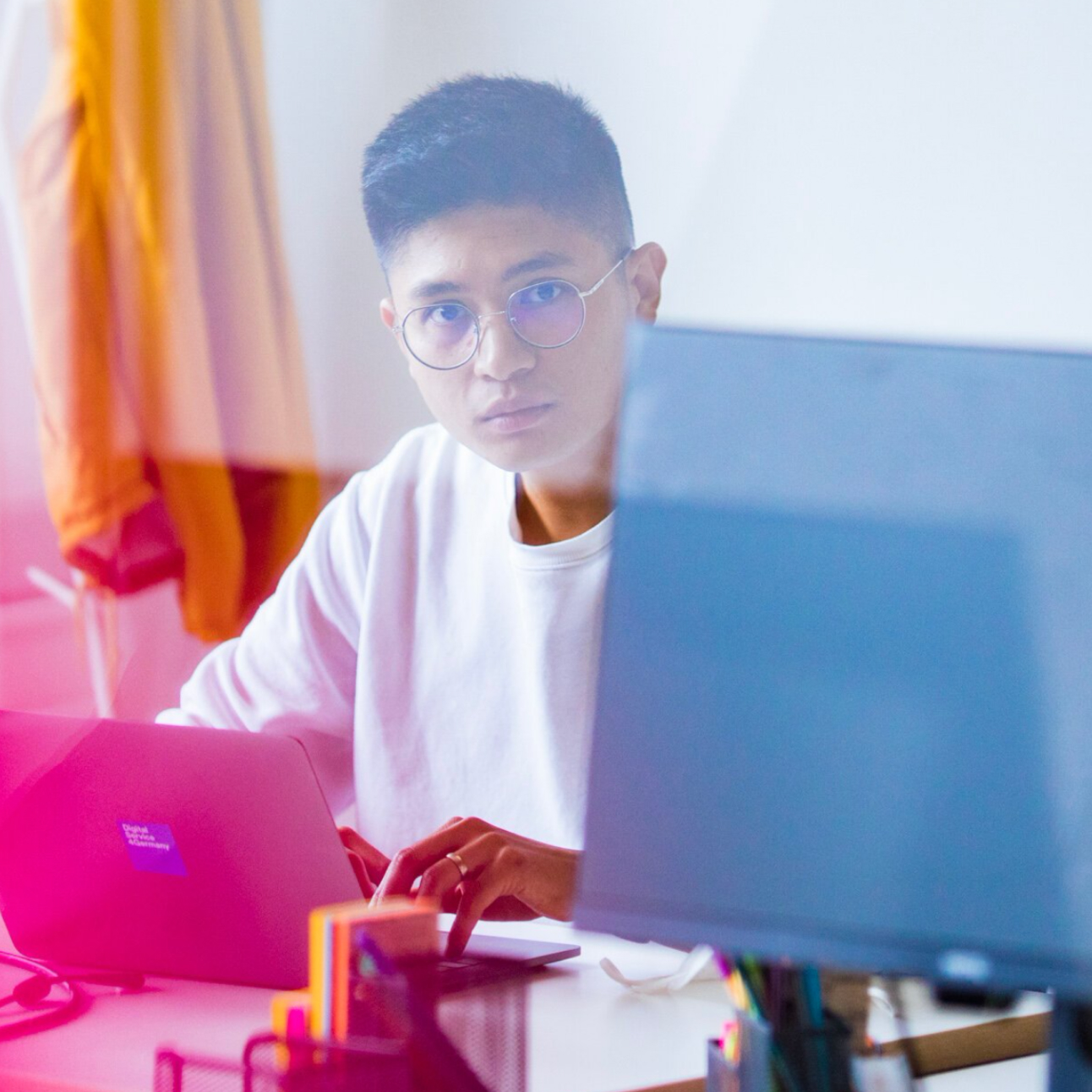 Mann sitzt im Büro am Laptop und schaut in die Kamera