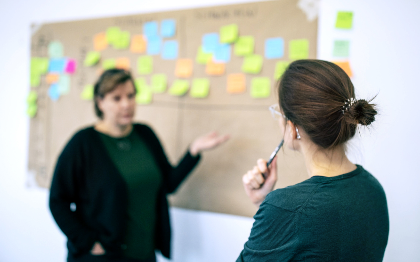 Frauen beraten sich an einer Wand mit Post-Its