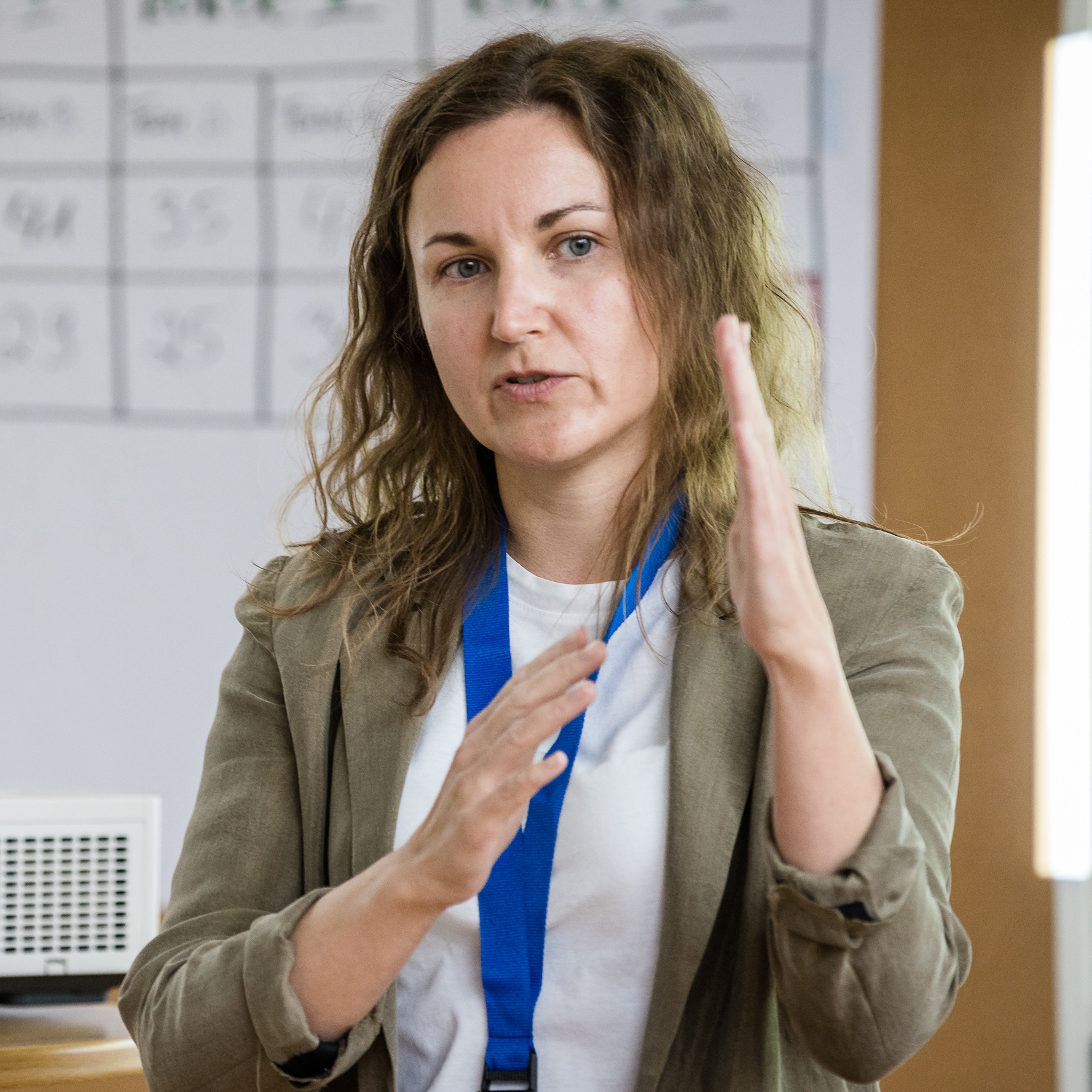 A portrait shot of a woman gesticulating and presenting.