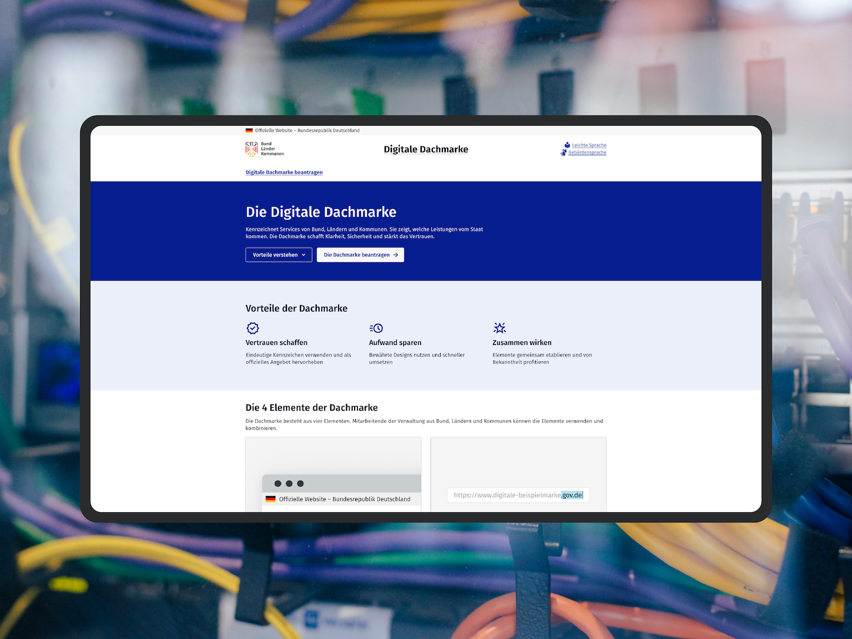 Screenshot der Website der „Digitalen Dachmarke“ auf einem Mock-up eines Bildschirms; als visuelles Stilmittel sieht man im Hintergrund das Büro des DigitalService