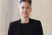 Dr. Julia Borggräfe steht vor einer hellbeigen Wand und blickt mit einem leichten Lächeln in die Kamera; sie trägt einen schwarzen Blazer über einem schwarzen Oberteil; ihre Haare sind kurz und grau meliert