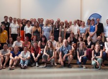 Gruppenfoto des 5. Tech4Germany Jahrgangs mit über 60 Stipendiaten und Projektpartnern. Sie stehen in einem Raum mit hohen Decken.  Links und rechts gibt hängen Vorhänge.