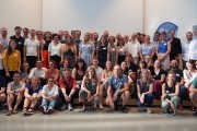 Gruppenfoto des 5. Tech4Germany Jahrgangs mit über 60 Stipendiaten und Projektpartnern. Sie stehen in einem Raum mit hohen Decken.  Links und rechts gibt hängen Vorhänge.