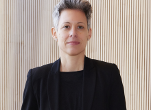 Dr. Julia Borggräfe steht vor einer hellbeigen Wand und blickt mit einem leichten Lächeln in die Kamera; sie trägt einen schwarzen Blazer über einem schwarzen Oberteil; ihre Haare sind kurz und grau meliert